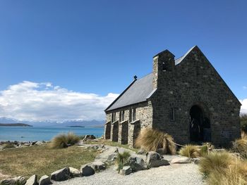 Built structure by sea against blue sky