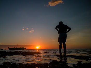 Silhouette man standing on beach against sky during sunset