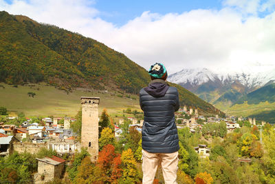 Man impressed by the amazing view of mestia town with svan tower among the fall foliage, georgia