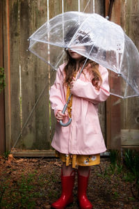 Girl holding umbrella while standing outdoors