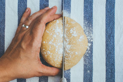 Cropped image of hand cutting bread on table at home