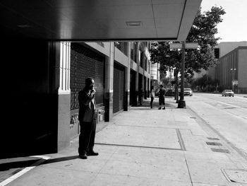 Man standing on sidewalk in city