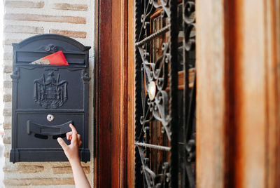 Cropped hand of person taking paper from post box