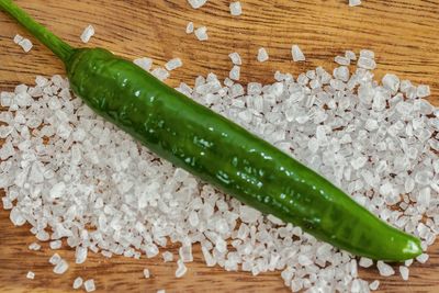 Close-up of green chili pepper on salt at table