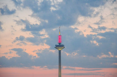 Low angle view of communications tower against cloudy sky