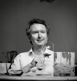 Smiling mature man holding drink glass while looking away at table