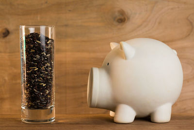 Close-up of piggy bank and food in glass on table