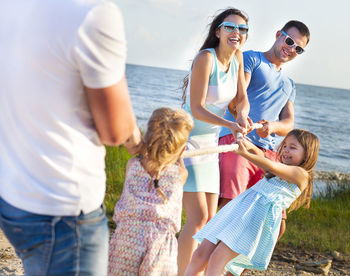 Cheerful family playing with rope during vacation