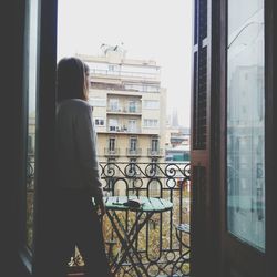 Rear view of woman looking through window