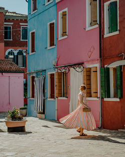 Young elegant woman standing in front of colorful houses in burano