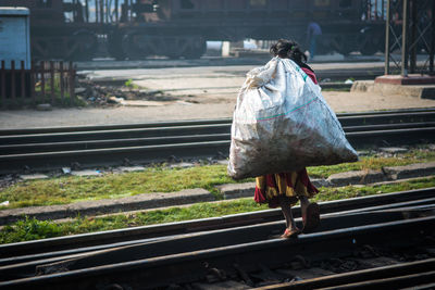 Rear view of woman walking on railroad track