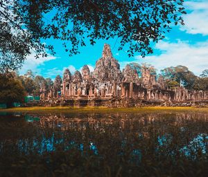 View of temple by lake against sky