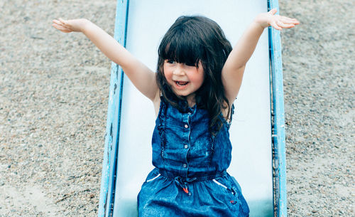 High angle view of cheerful girl on slide at playground