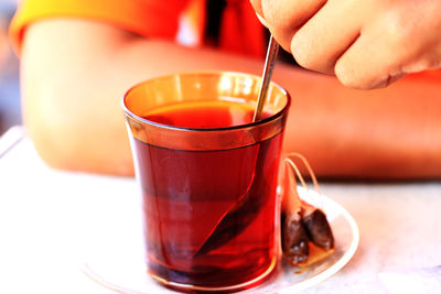 Cropped image of person stirring herbal tea