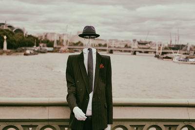 Man wearing suit while standing against river in city