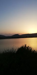 Scenic view of lake against clear sky during sunset