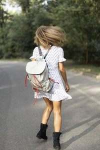 Rear view of woman tossing hair while standing on road