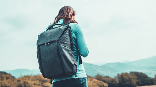 Rear view of woman walking on mountain against sky