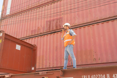 Low angle view of man working against orange wall