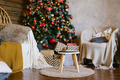 Christmas gifts lie on a stool near a christmas tree in the interior of a country house