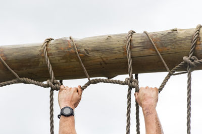 Low angle view of man holding rope against clear sky