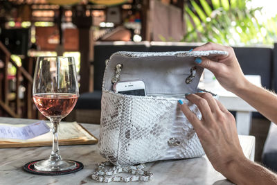 Midsection of woman holding wine glass on table at restaurant