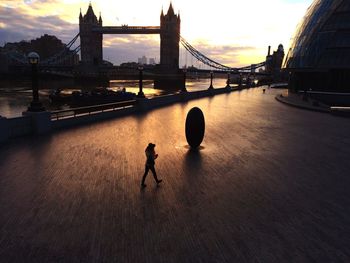 Suspension bridge over river at sunset