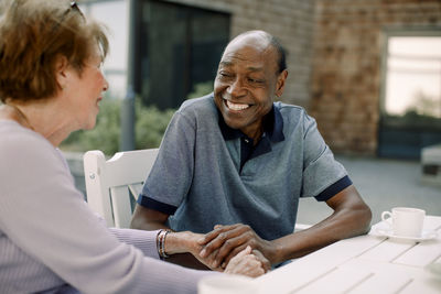 Happy senior man talking to woman while sitting at dining table