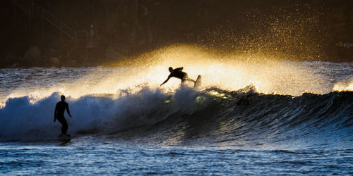 Silhouette man surfing in sea against sky