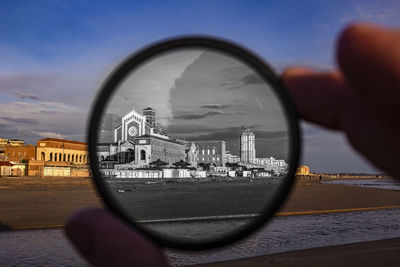 Close-up of hand on glass against buildings in city