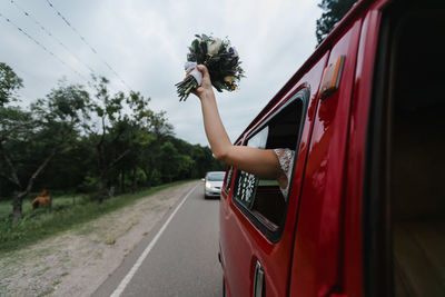 Woman on red car against sky