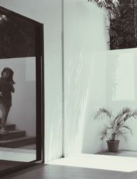 Young woman reflecting in mirror while standing moving down from steps at terrace