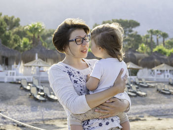 Mother holds her little son. beach vacation. warm sunset light and strong wind. family life.