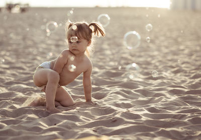 Cute girl playing with bubbles on sand at beach