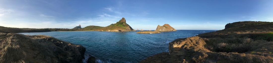 Panoramic view of sea and rocks against blue sky