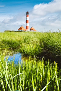 Lighthouse on field against sky