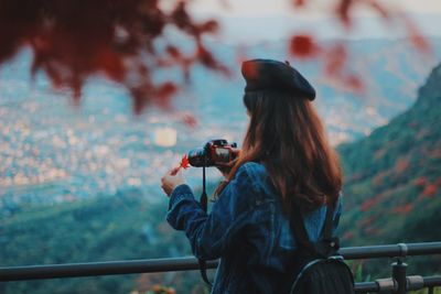 Woman photographing maple leaf with digital camera during autumn