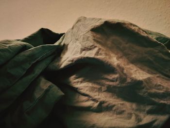 Close-up of person relaxing on bed against wall at home