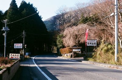 Road by trees against clear sky