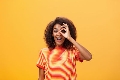 Portrait of smiling woman gesturing against colored background