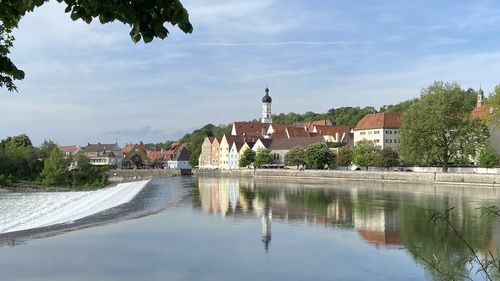 Buildings by lake against sky