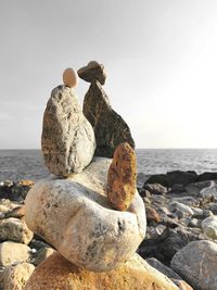 Stone stack on rock at beach against sky