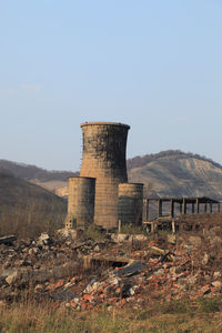 Old abandoned factory on field against sky