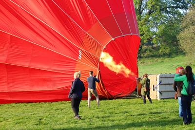 People standing by hot air balloon on grassy field