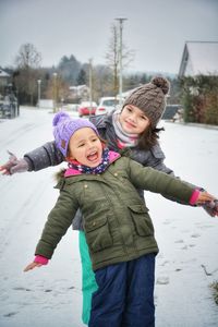 Portrait of smiling girl standing against snow during winter