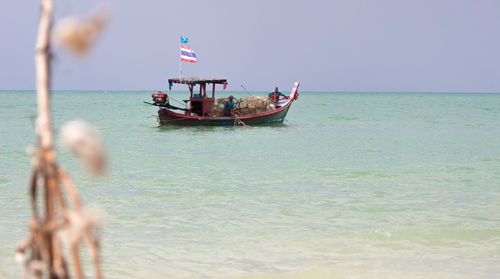 Fishing boat in sea against clear sky