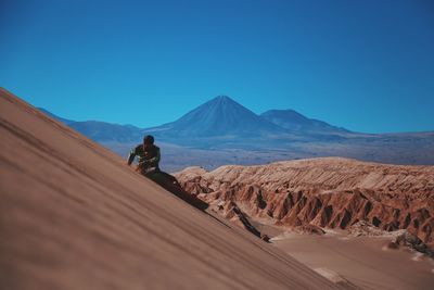 Man on desert against clear blue sky