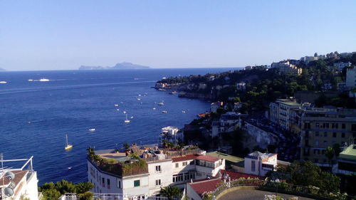 High angle view of cityscape by sea against clear sky