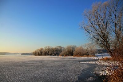 Scenic view of frozen landscape against clear blue sky