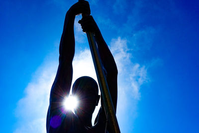 Low angle view of silhouette metallic structure against blue sky on sunny day